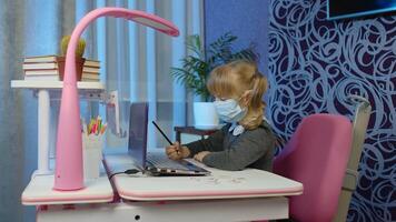 Child schoolgirl learning lessons with teacher being at home sitting at table using digital laptop computer. Portrait of a kid pupil girl distance education. Studying during coronavirus quarantine video