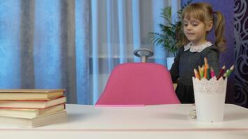 Child girl looking at web camera making call learning, studying lessons at home, reading book, smiling. Online pupil distance internet education lesson for children kids on coronavirus lockdown video