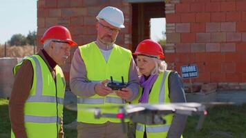 Specialist use drone on construction site. Architectural engineer, safety engineering inspector fly on building construction site controlling quality. Showing house to grandparents clients family video