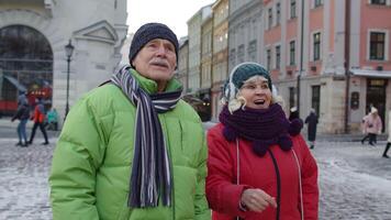 Slow motion of elderly mature people tourists walking in old city in winter talking and gesturing enjoying conversation, having fun. Senior families and communication holidays vacation trip concept video