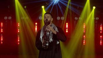 Arabian saxophonist in nightclub playing sax, dancing, performing on concert musician stage. Live performance of emotional man with saxophone. At the end of the performance he blows up the fireworks video