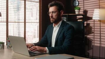 Caucasian middle-aged business man typing laptop in office smiling looking at camera mature businessman working computer online chatting consulting client internet job male employer happy at table video