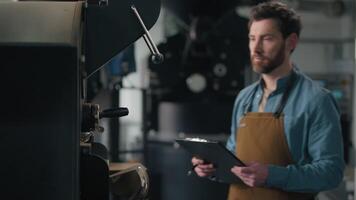 Caucasian man check roaster machine smell roasted coffee beans flavor check quality roasting control checklist middle-aged guy male barista working with caffeine small business owner industry factory video
