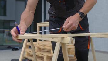 Close-up of man measuring wooden plank using tape and pencil. Carpenter working on construction project. Concept of craftsmanship, woodwork and renovation work video
