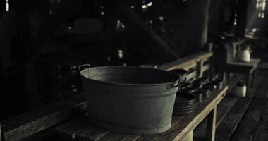 CGI Old metal bucket on wooden table in dark rustic setting with dishes video