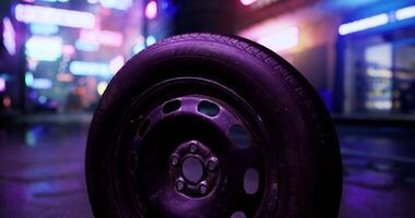 CGI Tire resting on wet pavement in neon lit urban setting at night video