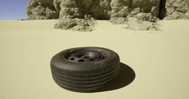 CGI Abandoned tire rests on desert sand beside rocky formation under clear sky video