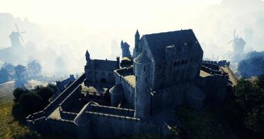 CGI Imposing medieval castle surrounded by mist and windmills at dawn video
