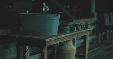 CGI Dark wooden table with metal utensils and a bucket in a rustic setting video