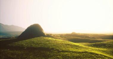 CGI Sunlight glows warmly over serene grassy hills and rocky formations video