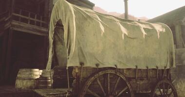 CGI Old wooden wagon covered with cloth parked beside barrels in rustic town video