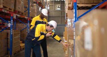 Two warehouse workers are reviewing the list of items based on the documentation,153 photo