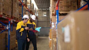 Two warehouse workers are reviewing the list of items based on the documentation,132 photo