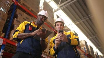 Two warehouse workers are reviewing the list of items based on the documentation,112 photo