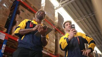 Two warehouse workers are reviewing the list of items based on the documentation,87 photo