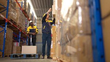 Two warehouse workers are lifting boxes of merchandise on a pallet jack to store on a shelf in a warehouse,72 photo