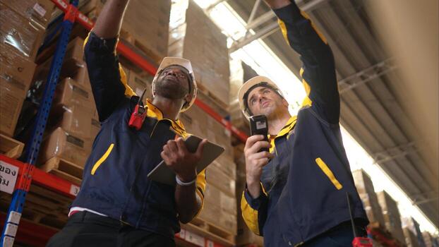 Two warehouse workers are reviewing the list of items based on the documentation,71 photo