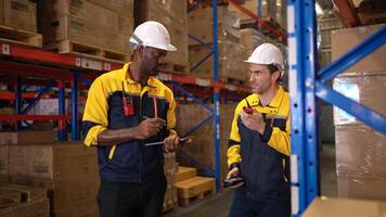 Two warehouse workers are reviewing the list of items based on the documentation,23 photo