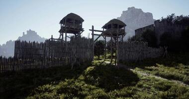 CGI Ancient fortification with wooden towers and mountain backdrop in daylight video