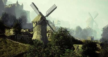CGI Windmills and ancient castle in misty hillside landscape at dawn video