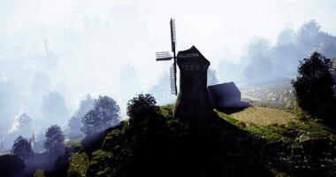 CGI Windmill sits atop hill surrounded by misty landscape in early morning light video