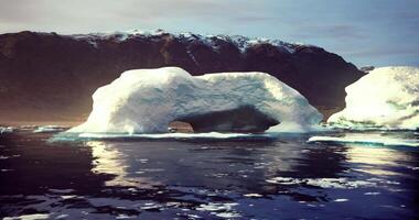 CGI Massive ice arch floats in calm waters near rugged mountains at dawn video