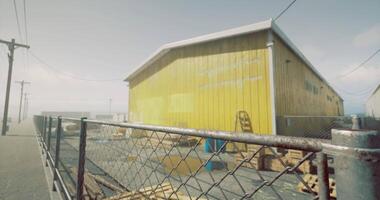 CGI Bright yellow building surrounded by a fence in a coastal area during daytime video