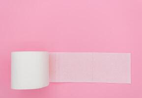 Top view of unrolled toilet paper at pink background photo