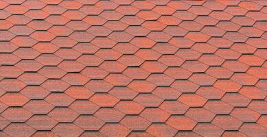 View of red bituminous roof tiles. Asphalt shingles roofing construction. Template for roofers photo
