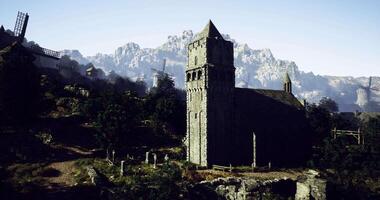 CGI Medieval church stands on hillside with windmills and mountains in background video