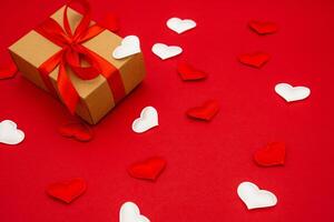 A small gift box on red background with hearts around. The concept of love photo