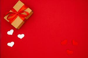 Top view photo of craft paper gift box with ribbon bow on isolated red background with copy space. The concept of the weddings, birthday and other holidays
