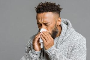 A man blowing his nose with a tissue photo