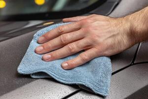 A person cleaning a car with a blue cloth photo