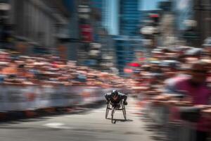A blurry image of a man in a wheelchair racing down a street photo