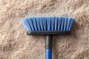 A blue brush is on top of a beige carpet photo