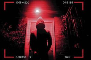 A person in a hoodie standing in front of a red light photo