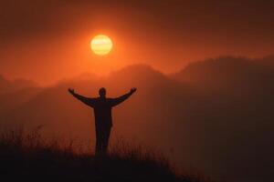 A man standing on a hill with his arms outstretched in front of the sun photo