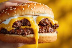 A hand holding a cheeseburger with cheese photo