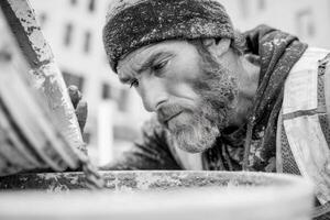 A man with a beard and a hat is pouring cement into a bucket photo