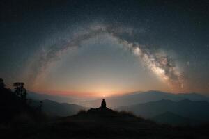 A person sitting on a hill looking at the milky photo