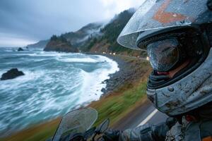 A person wearing a helmet and riding a motorcycle near the ocean photo