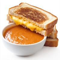 A golden-brown grilled cheese sandwich with melted cheddar oozing between two crispy slices of buttered bread. Served alongside a bowl of tomato soup for the ultimate cozy meal. Isolated on clean white background photo