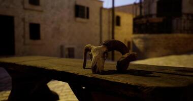 CGI Rustic setting with ram skull placed on wooden table in ancient village video