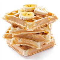 A stack of golden Belgian waffles with deep pockets, generously drizzled with honey and topped with sliced bananas. The waffles are crispy on the outside and fluffy inside, making for a mouthwatering breakfast option. Isolated on clean white background photo