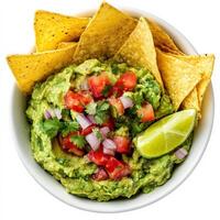 A bowl of fresh guacamole made with mashed avocados, diced tomatoes, onions, cilantro, and a squeeze of lime juice. The vibrant green dip is served with crispy tortilla chips for a classic Mexican appetizer. Isolated on clean white background photo