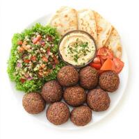A plate of freshly made falafel balls, crispy on the outside and soft inside, served with hummus, pita bread, and a side of fresh tabbouleh salad. A Mediterranean delight. Isolated on clean white background photo