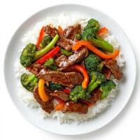 A plate of beef and vegetable stir-fry with tender strips of beef, bell peppers, broccoli, and carrots, tossed in a savory soy and ginger sauce, served over steamed rice. Isolated on clean white background photo