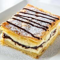 A close-up of a sweet and decadent mille-feuille dessert, a classic French pastry, with layers of crisp and flaky puff pastry, alternating with layers of smooth and creamy vanilla pastry cream, dusted generously with powdered sugar, and sometimes drizzled photo
