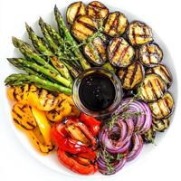 A vibrant platter of mixed grilled vegetables, featuring zucchini, eggplant, bell peppers, asparagus, and red onions, marinated in olive oil and herbs, and grilled until tender and slightly charred, served with a side of balsamic glaze, isolated on clean photo